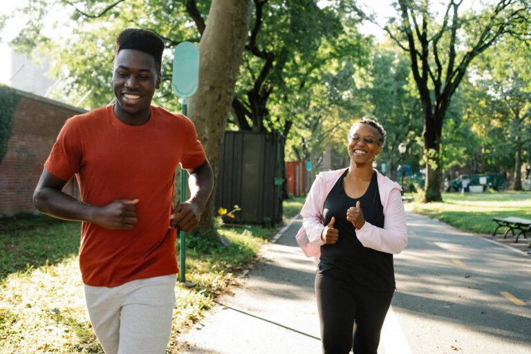A smiling couple jogging together in a sunny park setting.